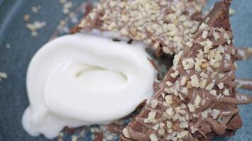 Chocolate dessert topped with nuts and cream is served video