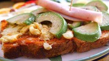 Savory open-faced sandwich topped with avocado and ham slices video