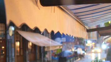 Rain falling on awnings in a busy urban area at dusk video