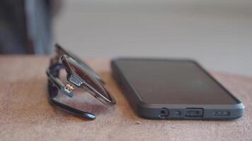Sunglasses and smartphone on a wooden table video