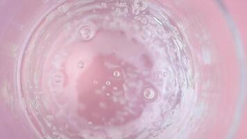Bubbles rise in clear glass with pink background video