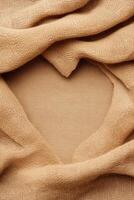 Woven Material Folds Creating Heart Shape. Light Brown Textile Background. Elegant Futuristic Fashion Concept. Delicate Fabric Texture Display. photo
