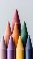 Colored crayon points arranged closely on gray surface. Vivid hues show details of tips. Row of art supplies points upward. Beautiful texture. photo