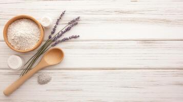 Wooden bowl with white powder and small jars beside lavender sprigs and spoon on light rustic wooden planks surface with copy space photo