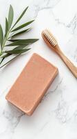 Soap block and brush on a marble surface. An olive branch lies nearby. Bathroom items on a stone countertop. Hygiene wellness product still life. photo