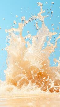 Beige liquid explodes upward. Droplets fly against a light blue sky. Water splashes with energy. A powerful stream surges from below. photo