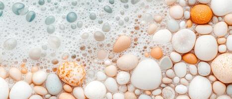 Smooth stones meet water bubbles. Close up view of ocean foam and pebbles on beach. Coastal scene with natural light. Pastel colors. photo