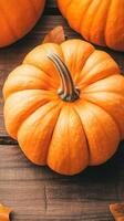 Orange pumpkins rest on weathered brown wood. Dried leaves are scattered around. Vertical orientation for seasonal designs. photo