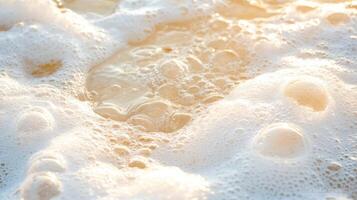 Ocean waves washing gently on sand with bright sunlight creates bubbles and light colored surface at beach during the day photo