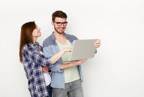 Couple conversation with laptop. Woman showing new dress to man on computer, he smiles in approval, white background, studio shot photo
