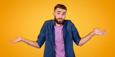 I don't know. Handsome Caucasian guy shrugging shoulders, feeling puzzled or uncertain on orange studio background. Confused millennial man expressing doubt, making difficult choice, panorama photo