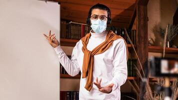 Indian Teacher In Face Mask Making Lecture For Educational Blog Teaching English Language Online, Pointing At Blackboard Explaining Grammar Standing Indoor. Distance Teaching And Education photo
