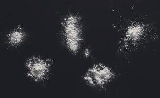 White flour splash spot on black background. Top view on blackboard. Baking concept, cooking dough or pastry. photo