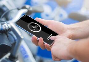 Smart bicycle travel, gadgets and activity control in city in spare time. Male hands press start of button on smartphone at mobile app on screen, on rent bikes blurred background, cropped, collage photo