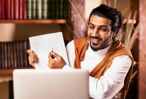 Remote Teaching And e-Learning. Indian Teacher At Laptop Having Online Class With Distant Student Sitting Indoors. Modern Tutoring, College And School Education Distantly, E-Teaching. Selective Focus photo