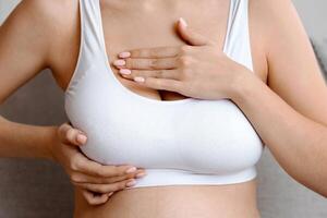 Breast Diseases During Pregnancy. Unrecognizable Pregnant Lady In Top Bra Massaging Chest Area While Sitting On Couch At Home, Expectant Lady Suffering Body Changes While Expecting Baby, Cropped photo