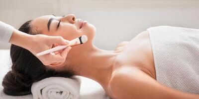 Relaxed asian woman enjoying beauty treatments in spa centre, waiting for beautician to apply facial clay mask, having wellness day at parlor, lying on massage table with closed eyes, side view photo