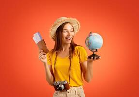 Exctited girl with passport, tickets, globe and camera over yellow studio background, going vacation photo