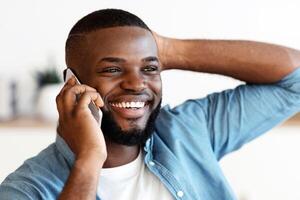 Mobile Call. Joyful African American Guy Talking On Cellphone And Smiling, Positive Black Man Having Pleasant Phone Conversation, Enjoying Modern Communication, Closeup Portrait With Selective Focus photo