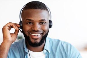 Call Center Operator. Closeup shot of friendly black man hotline manager in headset, portrait of handsome african american customer service representative looking at camera and smiling, free space photo
