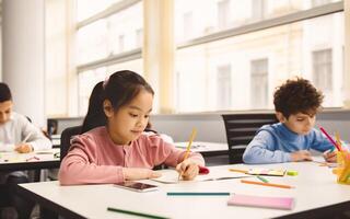 Learning Process Concept. Portrait of Small Schoolchildren Smiling, Sitting At Desk Taking Notes And Writing in Exercise Copybook. Junior Classroom with Diverse Group of Children Learning New Stuff photo
