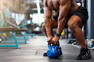 Cropped of black muscular man hands lifting kettlebell in empty gym. Unrecognizable african american guy bodybuilder building up muscles with iron ball, powerlifting concept, copy space photo