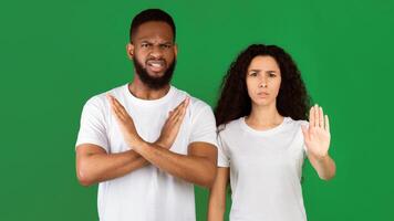 Don't Do It. Multiethnic Woman And Man Gesturing Stop And Crossing Hands Forbidding And Disapproving Something Standing On Green Studio Background. Restriction, Warning Concept. Panorama photo