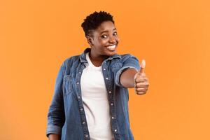 Cheerful Overweight African American Lady Gesturing Thumbs Up To Camera Approving Something Posing Standing On Yellow Studio Background. I Like It, Thumbs-Up Gesture Concept photo