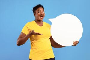 Happy Black Lady Posing With White Speech Bubble Showing Her Opinion And Thoughts Standing Over Blue Studio Background, Smiling To Camera. Feedback, Comment Concept. Mockup photo