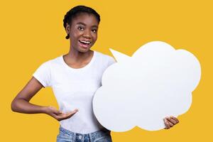 Smiling African Woman Showing Empty Thought Bubble Posing Standing Over Yellow Studio Background, Wearing Casual Clothes. Speech Bubble Mockup, Here's What I Think, My Opinion And Feedback Concept photo