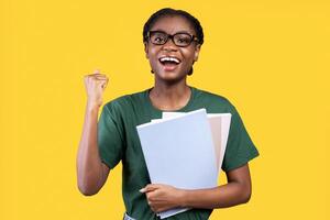 African Student Girl Gesturing Yes After Successful Exam Holding Notebooks Posing Smiling To Camera Standing Over Yellow Studio Background. Yes, I Got An A. End-Of-Semester Exams, Students Lifestyle photo