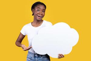 Speech Bubble Mockup. Cheerful Black Young Lady Showing Blank Thought Bubble Standing In Studio Over Yellow Background. My Feedback And Opinion. Here's What I Think Concept photo