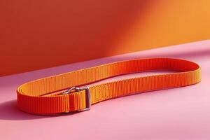 An orange belt with a buckle on a pink surface photo