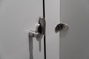 Close-up of a modern cabinet featuring a sleek metal lock and handle. The design showcases a minimalist approach, ideal for contemporary interiors, emphasizing both style and security photo