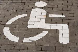 Pavement features a clear white symbol indicating a designated parking space for individuals with disabilities photo