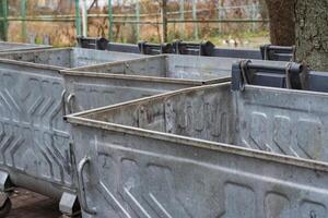 Metal containers sit in a bustling urban park, filled with plastic and organic waste. It serves as a reminder of the ongoing need for environmental conservation and proper waste disposal practices photo
