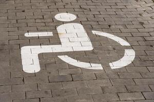 A white symbol indicating wheelchair accessibility is painted on a paved surface, highlighting the importance of inclusive transport options for people with disabilities in urban areas photo