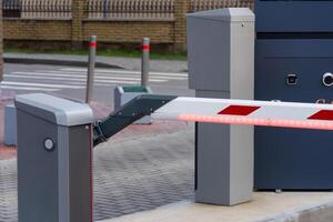An automated security barrier stands firmly at a parking lot entrance, ensuring controlled access for vehicles. Red lights indicate that entry is restricted, enhancing safety protocols photo