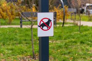 A sign clearly indicates that dogs are not allowed in this park area. It features a bold symbol of a dog crossed out, promoting cleanliness and safety for all park users photo