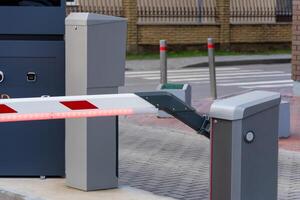 A closed automatic barrier secures the entrance to a parking lot, preventing unauthorized vehicle access. It is part of a safety control system, ensuring boundary integrity photo