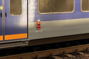 A blue and gray electric train is stationed on the railway platform, highlighting its modern industrial design and functionality. The train stands still, waiting for passengers at noon photo