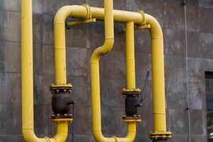 Yellow gas pipes are installed on a building's exterior, connecting energy sources effectively. The arrangement illustrates technology and infrastructure for fuel distribution in urban environments photo