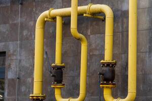 Yellow metal gas pipes connect multiple valves on a building's exterior, facilitating the safe transport of energy. The infrastructure shows the integration of technology in urban energy systems photo