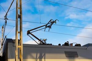 An electric train operates efficiently under clear blue skies, with its pantograph extended to connect with overhead supply lines. This showcases the advancement in railway technology photo