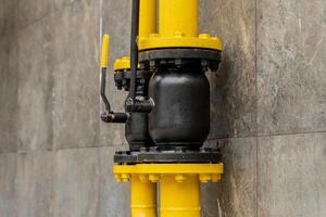 A connection in a gas pipeline system is displayed, showcasing black and yellow metal pipes and valves designed for efficient fuel distribution and control photo