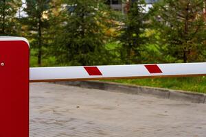 An automatic security barrier is positioned at the entrance of a parking lot, ensuring controlled access and safety for vehicles. The closed gate features red and white markings photo