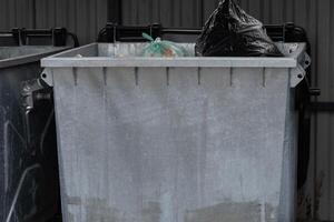 A metal garbage container overflowing with trash underscores the importance of waste management and recycling for promoting environmental sustainability in urban areas photo