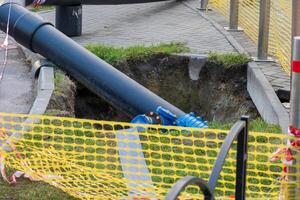 Workers are engaged in replacing water pipes on the street, utilizing heavy machinery to dig and install new pipelines amidst construction hazards and safety barriers photo