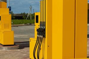 Bright yellow gas dispensers are prominently positioned at a fuel station, offering a convenient refueling option for vehicles on a clear day. The surroundings are open and spacious photo