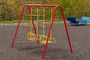 Brightly colored swings and a climbing frame stand in a public park, offering a playful setting for children to enjoy outdoor activities. This joyful space promotes fun and happiness photo